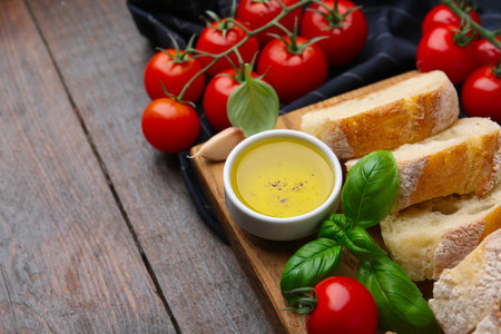 Tasty baguette served with butter, tomatoes and basil on wooden table, closeup. Space for textの写真素材