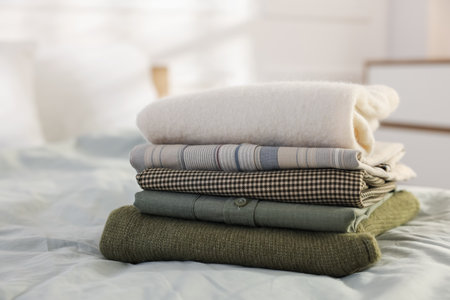 Stack of clean clothes on bed indoors, closeup. Space for textの写真素材
