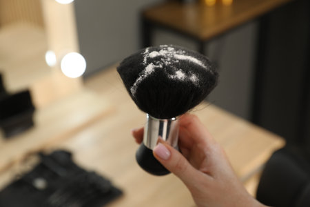 Hairstylist holding brush with talcum powder at salon, closeup. Space for textの写真素材