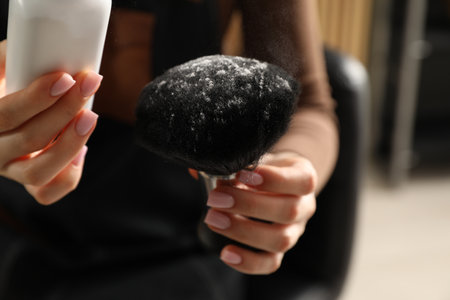Hairstylist holding brush with talcum powder at salon, closeupの写真素材