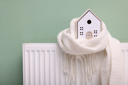 House model with scarf on heating radiator near green wallの写真素材