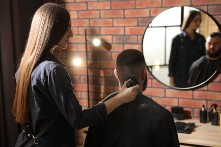 Hairstylist applying talcum powder with brush onto man's neck at salonの写真素材