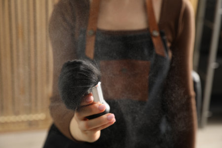Hairstylist holding brush with talcum powder at salon, closeupの写真素材