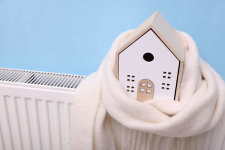 House model with scarf on heating radiator near light blue wall, closeupの写真素材