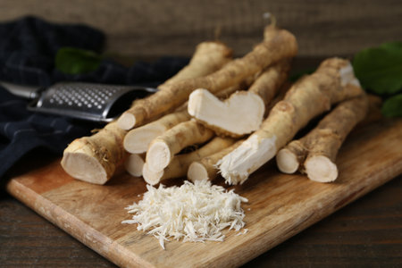 Grated horseradish, grater and fresh roots on wooden table, closeupの写真素材