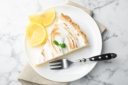 Slice of tasty lemon meringue tart with mint served on white marble table, top viewの写真素材