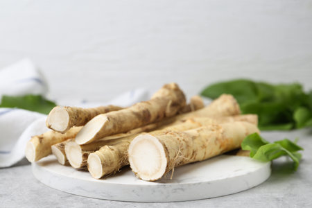 Fresh raw horseradish roots and leaves on light gray table, closeupの写真素材