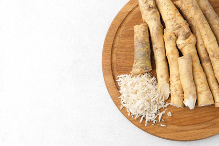 Whole and grated horseradish roots on light gray table, top view. Space for textの写真素材