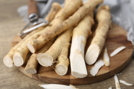 Fresh raw horseradish roots and peeler on wooden table, closeupの写真素材