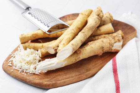 Grated horseradish, grater and fresh roots on white table, closeupの写真素材