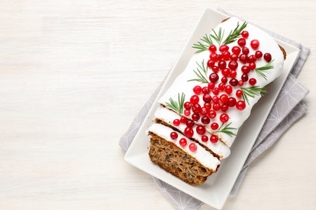 Tasty Christmas cake with icing, cranberries and rosemary on white wooden table, top view. Space for...