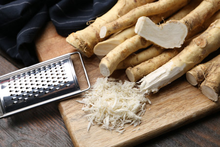 Grated horseradish, grater and fresh roots on wooden table, closeupの写真素材