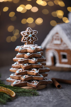 Christmas tree made of gingerbread cookies, cinnamon, dried orange slice and fir branch on gray table against blurred lights, closeupの写真素材