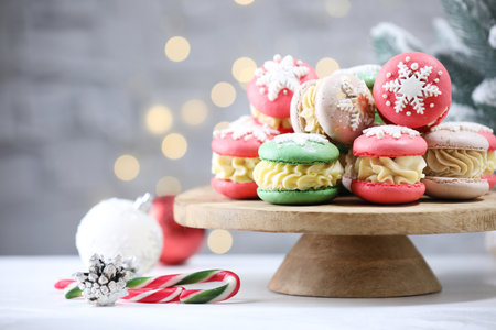Tasty macarons and Christmas decor on white table against blurred lights. Space for textの写真素材