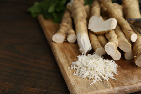 Grated horseradish, leaves and fresh roots on wooden table, closeup. Space for textの写真素材
