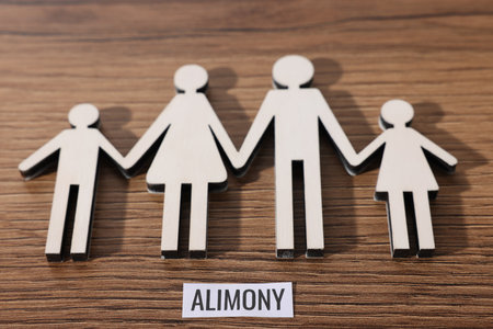 Paper note with word Alimony and figures of family on wooden table, above viewの写真素材