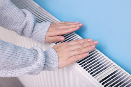 Woman warming her hand near radiator indoors, closeupの写真素材