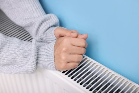 Woman warming her hand near radiator indoors, closeupの写真素材