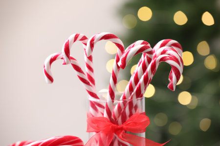 Candy canes in glass against blurred lights, closeup. Christmas treatの写真素材