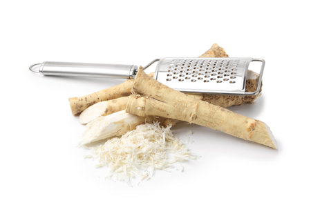 Grated horseradish, grater and roots isolated on whiteの写真素材