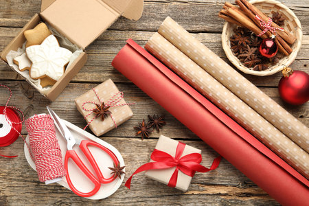 Festive packaging. Gift boxes, wrapping paper, twine, scissors, cookies and spices on wooden table, flat lay. Merry Christmas and Happy New Yearの写真素材