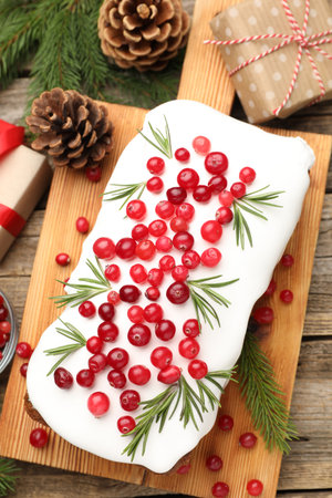 Tasty Christmas cake with cranberries, gift boxes and fir cones on wooden table, flat layの写真素材