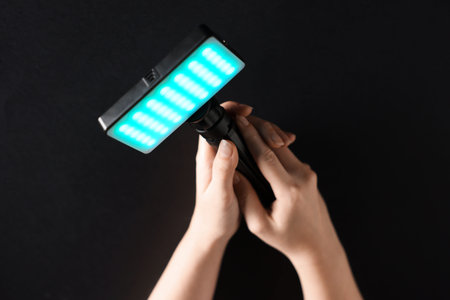 Woman with glowing LED lamp on black background, closeupの写真素材