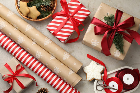 Festive packaging. Gift boxes, wrapping paper, gingerbread cookies, ribbon and scissors on light textured table, flat lay. Merry Christmas and Happy New Yearの写真素材