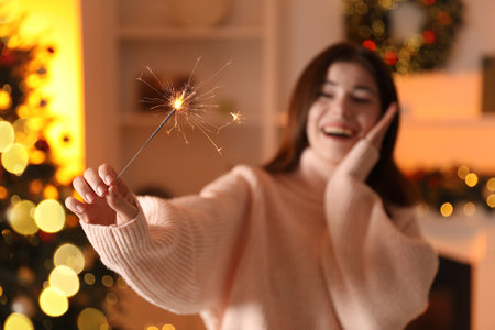 Happy woman with sparkler celebrating Christmas at home, selective focusの写真素材