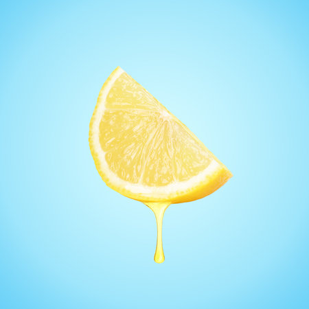 Drop of juice dripping from citrus fruit. Fresh lemon wedge on light blue backgroundの写真素材