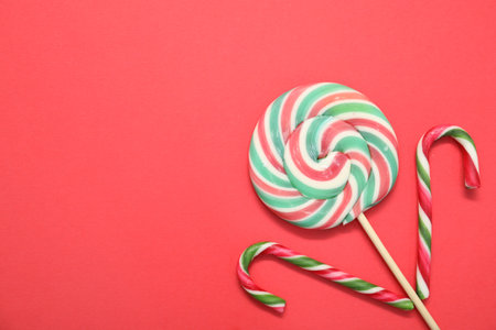 Christmas treat. Lollipop and candy canes on red background, top view. Space for textの写真素材