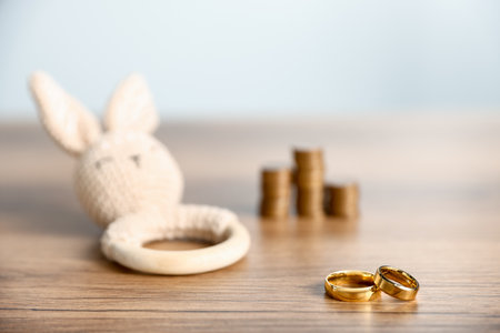Engagement rings, teething toy and coins on wooden table against light gray background, selective focusの写真素材