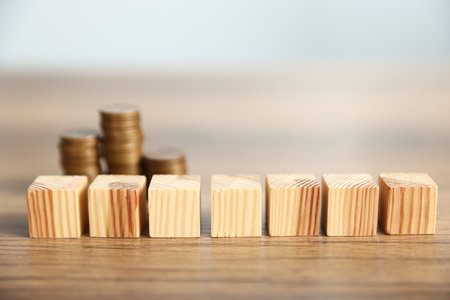 Alimony. Blank cubes and coins on wooden table against light gray background, selective focusの写真素材
