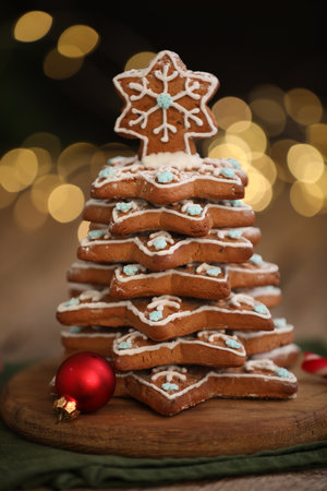 Christmas tree made of gingerbread cookies and ornaments on wooden table against blurred lights, closeupの写真素材