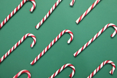 Christmas treat. Candy canes on green background, flat layの写真素材