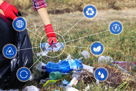 Woman putting garbage into plastic bag in park, closeup. Scheme with recycling symbol and different...