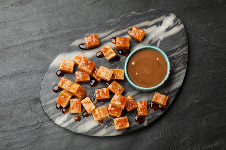 Tasty candies with salt and caramel sauce on dark textured table, top viewの写真素材