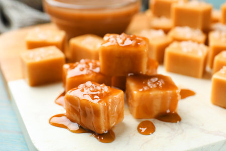 Tasty candies with salt and caramel sauce on light table, closeupの写真素材