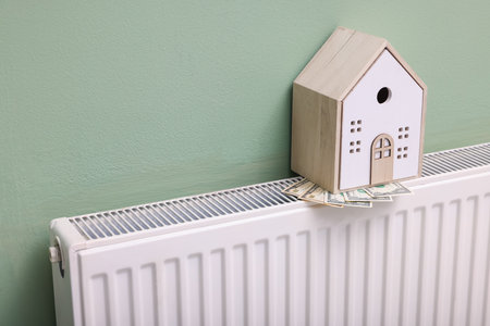 House model and dollar banknotes on heating radiator near green wall, closeupの写真素材