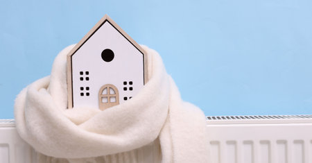 House model with scarf on heating radiator near light blue wall, closeupの写真素材