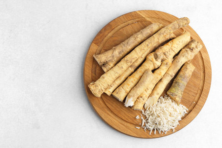 Whole and grated horseradish roots on light gray table, top view. Space for textの写真素材