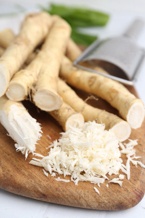Grated horseradish, grater and fresh roots on white table, closeupの写真素材