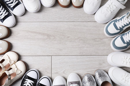 Frame of many stylish kid's shoes on gray wooden floor, flat lay. Space for textの写真素材