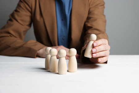 Woman with human figures at white wooden table, closeupの写真素材