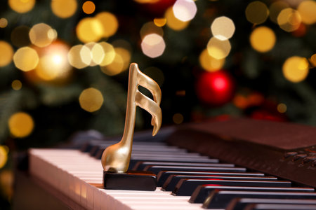 Golden music note on piano near Christmas tree indoors, space for text. Bokeh effectの写真素材