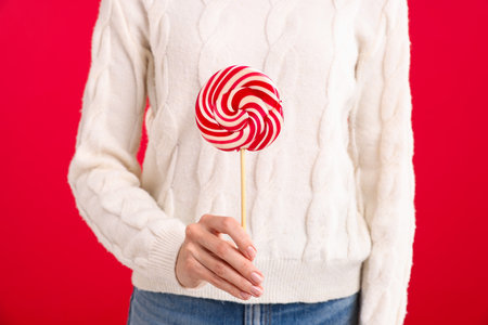 Woman in white sweater with lollipop on red background, closeup. Merry Christmas and Happy New Yearの写真素材