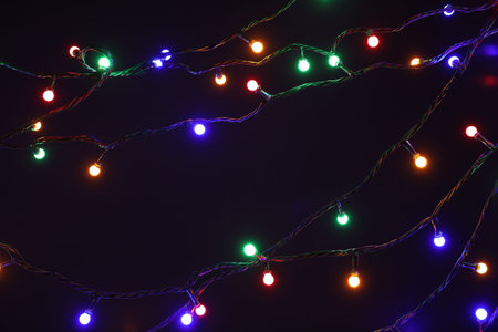 Bright Christmas lights on dark background, closeup