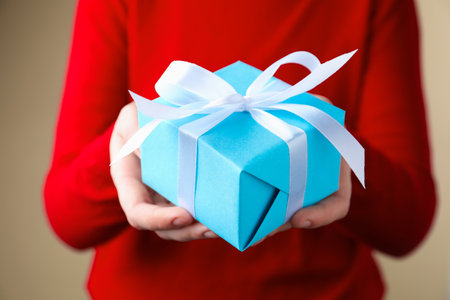 Woman with gift box on beige background, closeupの写真素材