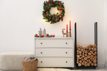 Christmas decor on cabinet and firewood near white wall indoors. Interior designの写真素材