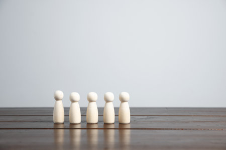 Many human figures on wooden table against light background. Space for textの写真素材